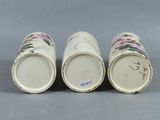three porcelain vases with floral designs on them sitting on a gray surface