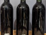 three bottles of wine are lined up on a wooden table