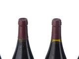 three bottles of wine are lined up in a row on a white surface