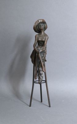 statue of a woman sitting on a stool with a hat on her head