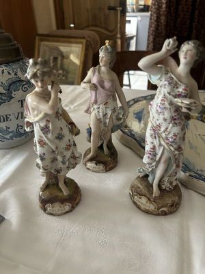 three figurines sitting on a table with a vase in the background