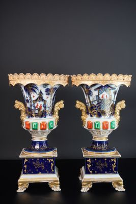 paire de vases bleus et blancs ornés de motifs dorés, posés sur des socles