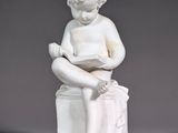 a white statue of a boy reading a book
