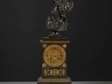 une statue d'un homme tenant une horloge au-dessus d'une table