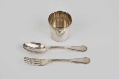 two spoons and a fork next to a silver cup