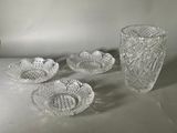four glass bowls and two vases on a table