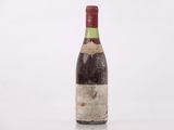 une vieille bouteille de vin posée sur une surface blanche