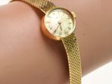le poignet d'une femme, sur lequel se trouve une montre en or