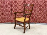 a wooden chair with a yellow seat in front of a red wall