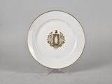 a white and gold plate with a crest on it
