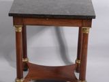 une vieille table en bois avec un plateau en marbre noir et des finitions en laiton