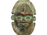 un gros plan d'un masque en bronze sur fond blanc