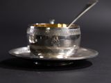 a silver cup with a spoon in it sitting on a saucer