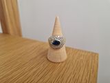 bague en argent et pierre bleue posée sur un cône en bois, lui-même posé sur une table en bois