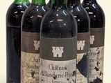 six bouteilles de vin sont alignées sur une surface blanche