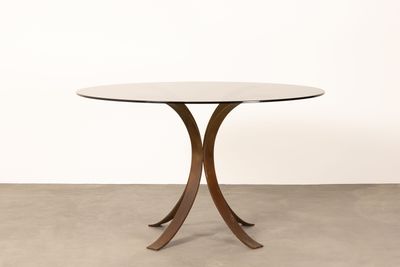 une table ronde avec un plateau en verre et un piètement en bois