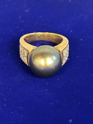 a close up of a ring with a pearl on a blue surface