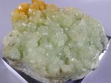 a piece of green and yellow crystal on a silver plate