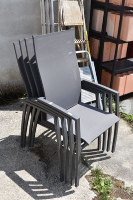 a stack of chairs sitting on a sidewalk next to a building