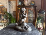 a statue of a boy playing a flute on a table