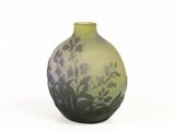 a green vase with flowers on it on a white surface