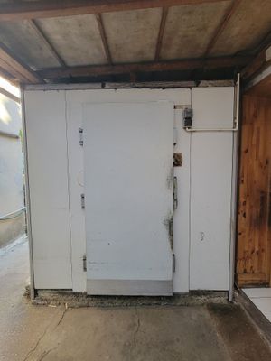 a white refrigerator in a garage with a wooden door