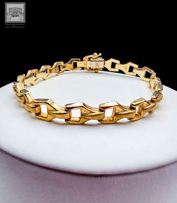 bracelet plaqué or à maillons et fermoirs, monté sur un socle blanc