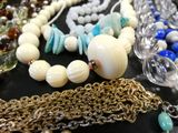 many different necklaces and bracelets on a table