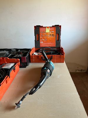 une perceuse posée sur une table, à côté d'une boîte à outils