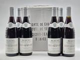 six bottles of red wine sit in front of a silver box