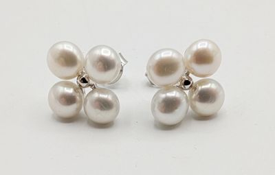 une paire de boucles d'oreilles en perles blanches et argent posées sur un fond blanc