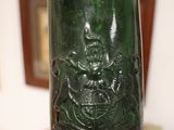 someone is holding a green glass bottle with a picture of a man on it