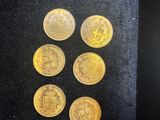 six gold coins in a black box with a black background