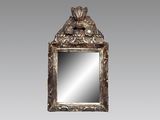 un miroir au cadre en argent ouvragé, orné d'un oiseau sur le dessus