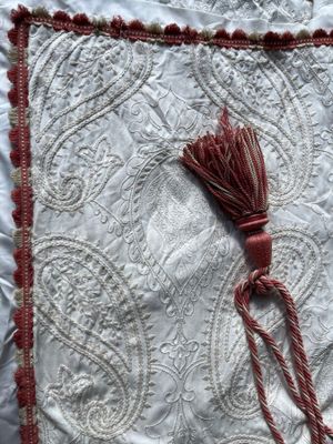 un gros plan sur un coussin blanc et rouge orné d'un pompon