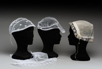 trois têtes de mannequin ornées de voiles et de dentelle