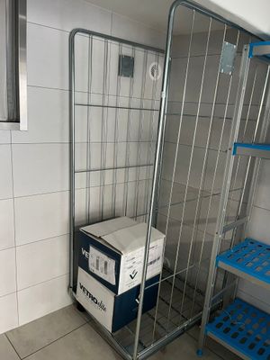 une cage métallique surmontée d'une boîte, dans une pièce