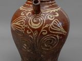 un vieux vase marron posé sur une surface grise