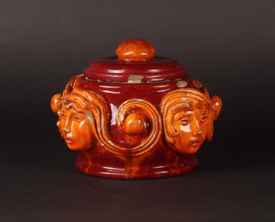 an orange and brown ceramic jar with three faces on it