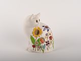 a white cat figurine with flowers painted on it