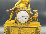 a gold clock with a statue of a woman sitting on top of it