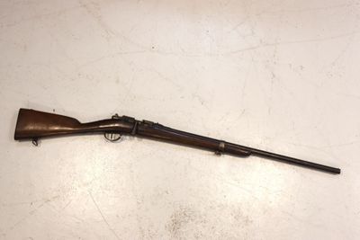 an old rifle is laying on the floor next to a wall