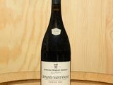 une bouteille de vin posée sur un tonneau en bois