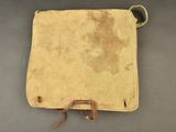 an old leather bag with a brown handle on a gray surface