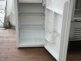 a white refrigerator with its door open on a wooden floor