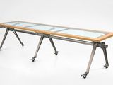 une image représentant une longue table avec un plateau en verre et des pieds en métal