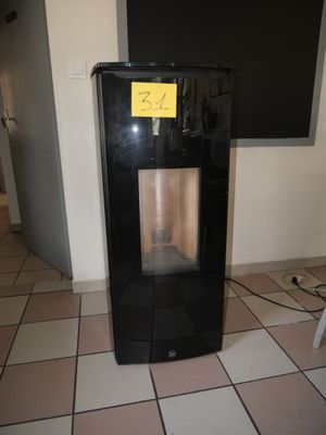 un réfrigérateur noir sur lequel est collé un autocollant jaune, dans une pièce