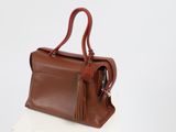 the brown leather handbag is sitting on top of a white box