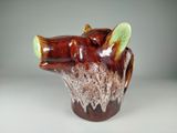 un vase marron et vert orné d'une tête d'ours