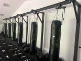 une rangée de sacs de frappe suspendus à un mur dans une salle de sport